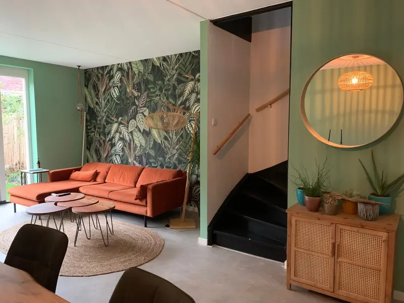 Woonkamer met botanisch behang op de trapwand